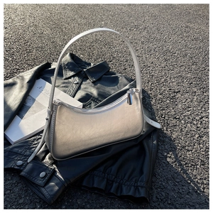 Detail of silver metallic crescent shoulder bag showing sleek texture on black leather