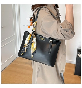 Detail of black leather tote bag with decorative printed scarf on the handle strap