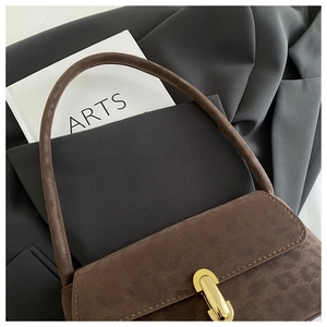 Detail of dark brown suede shoulder bag with elegant gold metal buckle and smooth texture