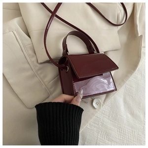 Detail of burgundy patent leather mini square bag with glossy finish and top handle