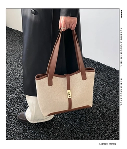 Detail of minimalist canvas tote with brown leather trim and golden buckle closure