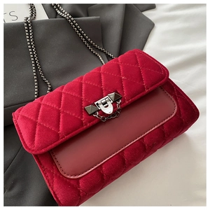 Detailed close-up of red velvet quilted crossbody bag with luxury metal lock and chain strap