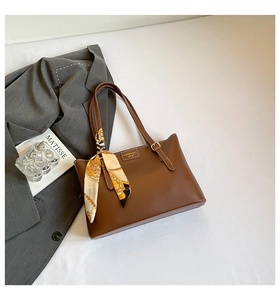 Brown leather tote bag detail with printed silk scarf and fashion logo plate