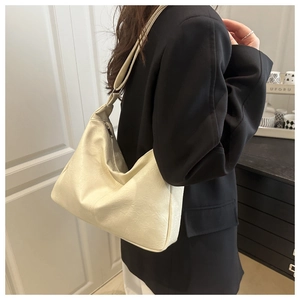 Détail d'un sac cabas en cuir crème avec une texture souple et une large bandoulière