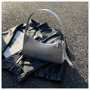 Macro detail of silver crescent shoulder bag with leather texture and metal zipper