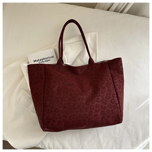 Deep red leopard print tote bag with a spacious design on a soft white texture background