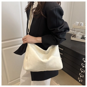 Gros plan d'un grand sac cabas en cuir texturé crème porté par un mannequin
