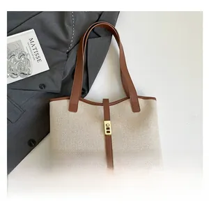 Detail of canvas tote bag with brown leather trim and gold buckle on a classic blazer