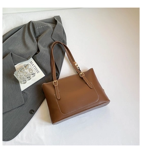 Detail of brown tote bag with white contrast stitching and gold buckle accents