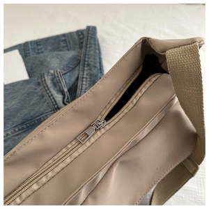 Detailed view of durable nylon crossbody bag with metal zipper and wide fabric strap