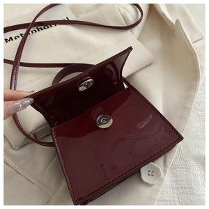 Detail view of burgundy patent leather bag showing magnetic closure and interior structure