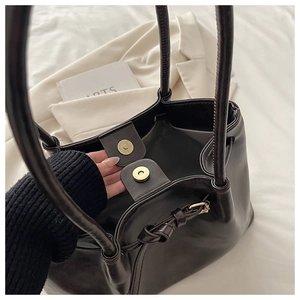 Detail view of large tote bag in dark brown faux leather with elegant gold hardware