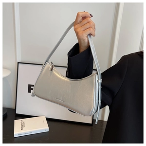 Detail of silver metallic baguette bag showing sleek texture and slender shoulder strap