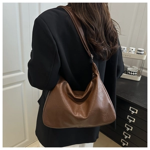 Détail du sac sous le bras en forme de croissant marron avec texture cuir souple