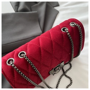 Detailed macro shot of red velvet quilted bag with elegant dark grey metal chain and lock