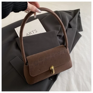 Close-up of a vintage brown suede shoulder bag with a gold metal twist lock and top handle