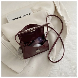 Detail of burgundy patent leather mini bag showing storage space for earbuds and small items