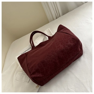 Detail of burgundy leopard print tote bag with reinforced handles on a white background