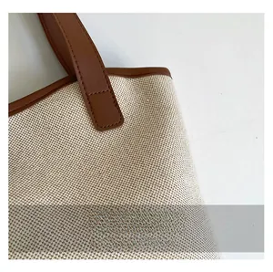 Detailed close-up of beige woven canvas texture and premium brown leather handle stitching