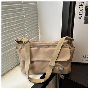 Detail of khaki nylon messenger bag with front flap pocket and fashion label accent