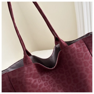 Detail of burgundy leopard print tote bag showing slim shoulder straps and grey lining