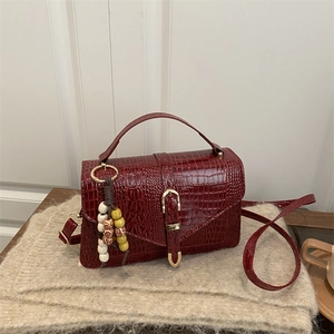 Dark red crocodile embossed handbag with gold buckle and decorative beaded keychain