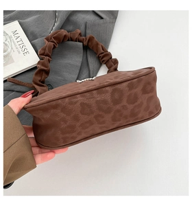 Détail du sac à main marron à motif léopard avec poignée froncée et finition en daim