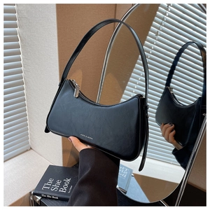 Detail of a black leather underarm bag with metal zipper and minimalist logo
