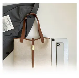 Spacious canvas tote bag with brown leather trim shown next to iPad and a blazer
