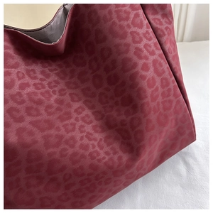 Close-up of luxury burgundy leopard print fabric texture on a fashion tote bag