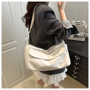 Detail of white nylon messenger bag with multiple pockets and Fashion logo on the flap