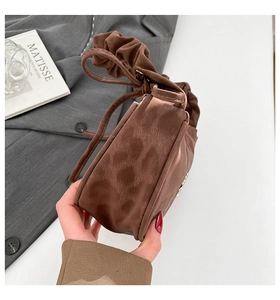 Détail d'un sac à main léopard avec finition en daim texturé et une poignée froncée