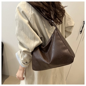 Détail d'un sac porté épaule hobo marron foncé vintage en cuir texturé au fini lisse
