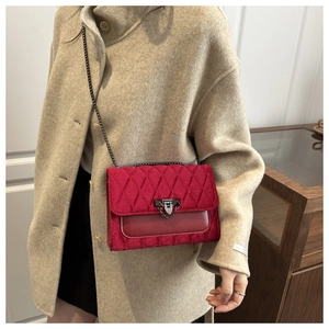 Detail of red quilted velvet crossbody bag with silver chain strap and metal clasp