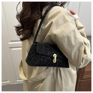 Close-up of leopard print underarm bag with gold oval buckle worn with a beige coat