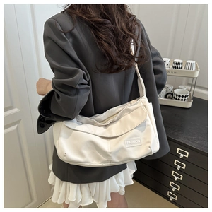 Detailed view of a white waterproof nylon messenger bag with fashion label on shoulder