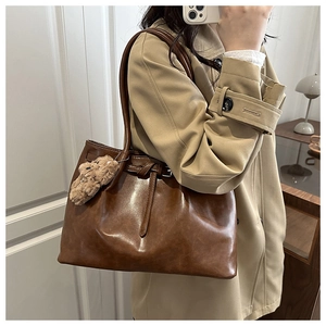 Brown vintage tote bag with teddy bear charm shown on model for daily commuting style