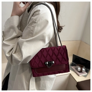 Macro shot of burgundy velvet quilted bag with metallic chain strap and twist-lock