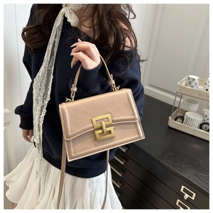Dettaglio borsa a tracolla beige con chiusura a incastro dorata indossata dalla modella