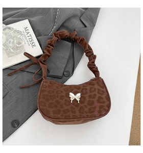 Détail du sac croissant léopard avec boucle papillon argentée et anse froncée design