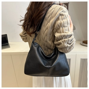 Vue arrière du modèle portant un sac hobo noir en similicuir avec bandoulière nouée