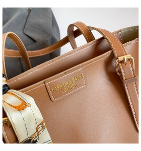 Detail view of brown faux leather tote bag with white contrast stitching and silk scarf accessory