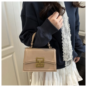 Detail of a vintage apricot crossbody bag featuring a golden metal buckle and top handle