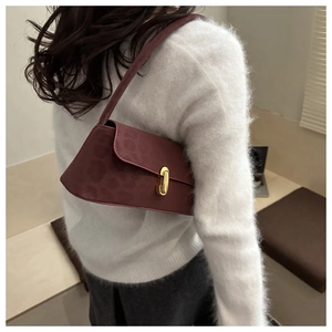 Detail of burgundy leopard embossed faux leather underarm bag with gold metal clasp