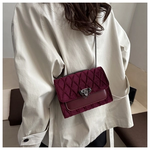 Detail view of burgundy quilted velvet crossbody bag with metallic chain strap and lock