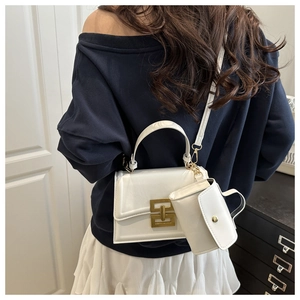 Modern white leather crossbody bag with gold chain buckle shown on model in minimalist setting