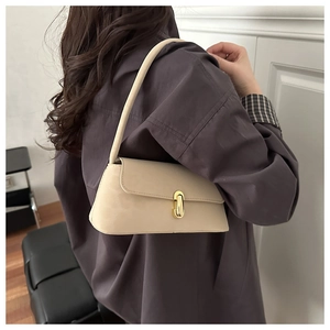 Detail showing creamy white shoulder bag with gold twist lock worn by a model
