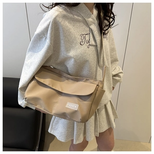 Detailed view of a beige nylon crossbody bag with large capacity and fashion label