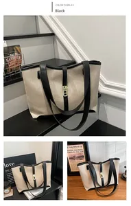 Detail shot of the cream canvas tote bag showing the gold twist lock and black leather trim
