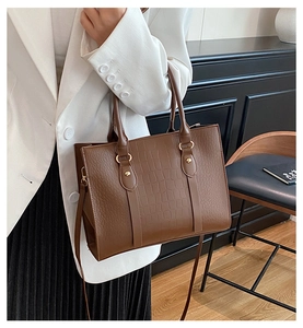 Close-up of caramel crocodile embossed tote bag with gold hardware and top handle